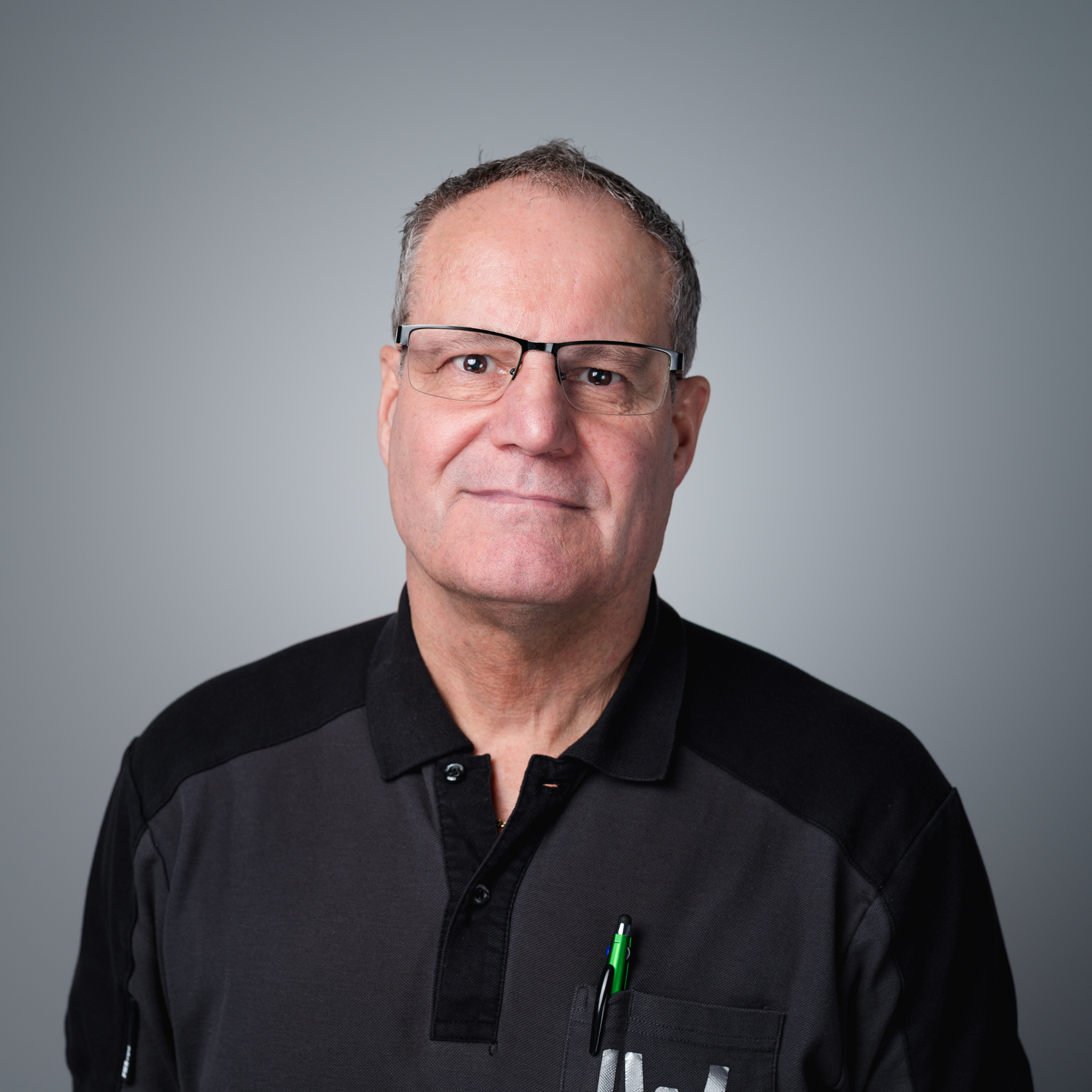 Porträt von Peter Rohlfing, einem Mann mittleren Alters mit Brille und dunklem Poloshirt, der freundlich in die Kamera blickt.