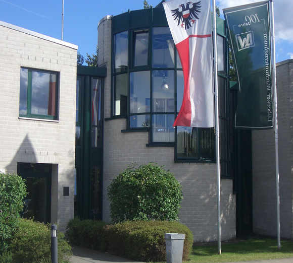 Außenansicht der Zentrale von Gorecki Maschinenbau mit zwei Fahnen vor dem modernen Gebäude aus hellen Ziegeln und großen Fenstern.